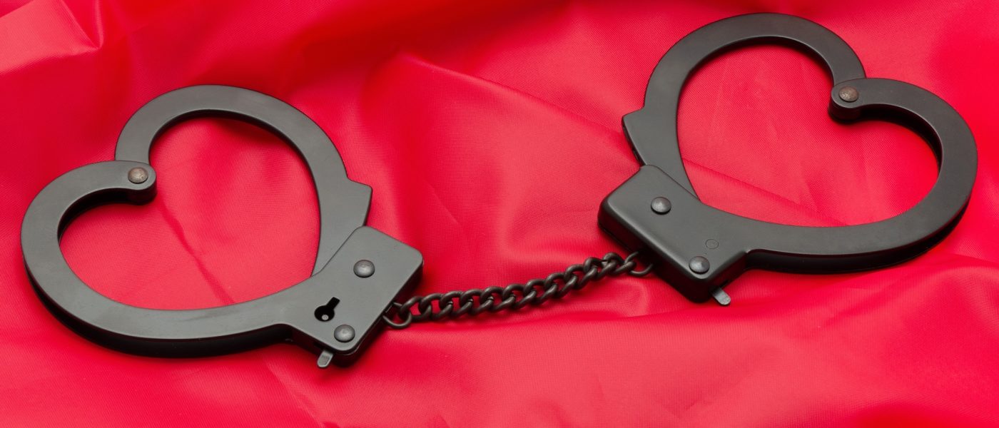 Sexy handcuffs placed on a red satin background