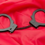 Sexy handcuffs placed on a red satin background