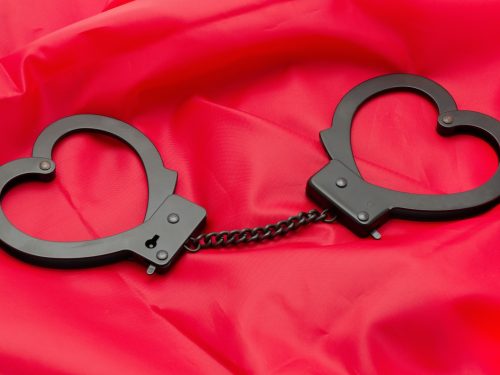 Sexy handcuffs placed on a red satin background