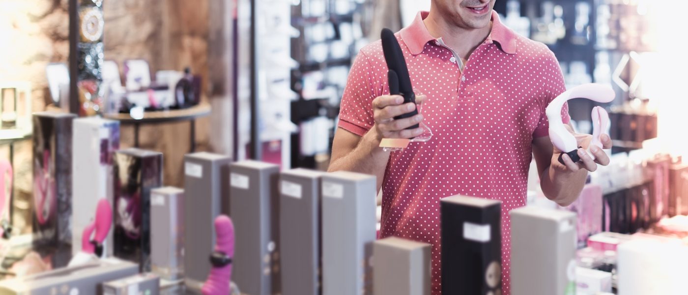 Adult man buyer choosing different sexy toys in the sex shop